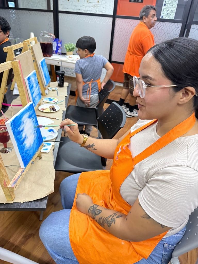 Alumna pintando un cielo azul en su lienzo