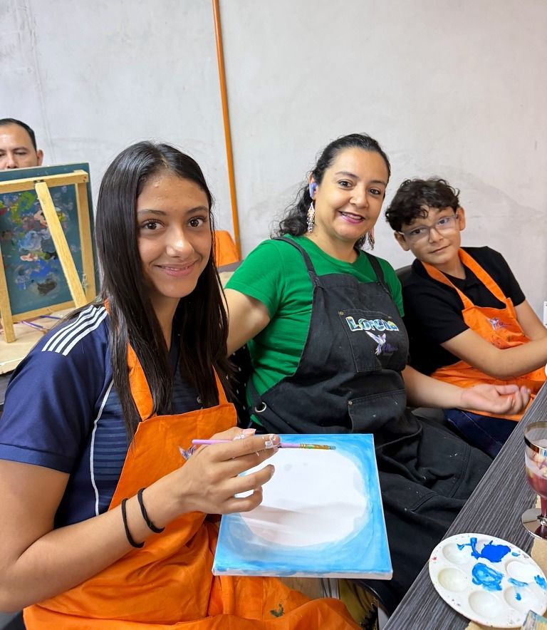 Tres participantes sonriendo con sus pinceles y paletas