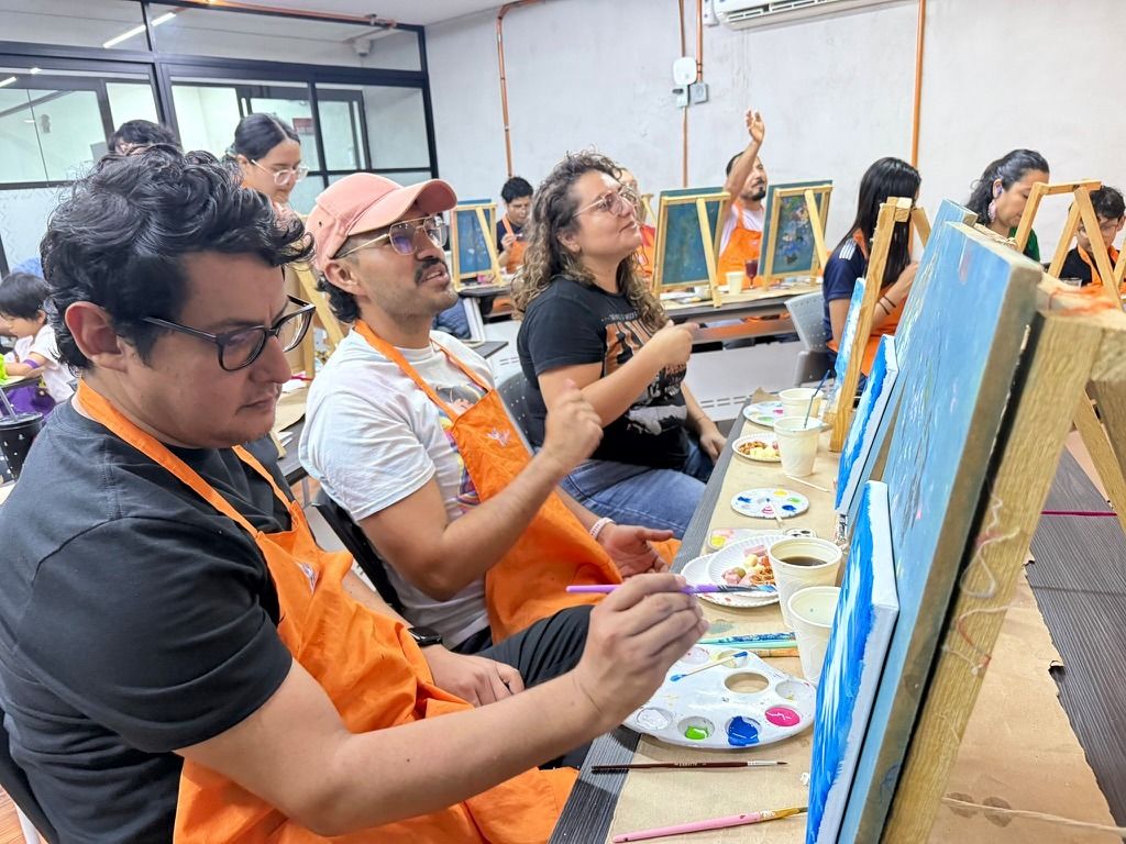 Mesa larga de participantes pintando en sus lienzos
